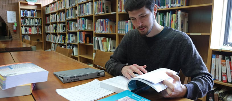A student studies in the library, sitting at a table. 