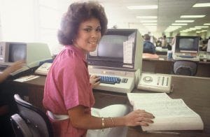 Bidwell Training Center in 1984, a woman sits at a desk with a book and a computer 