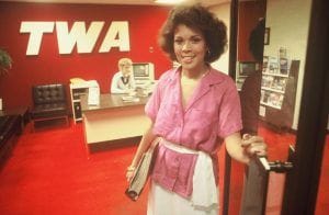 A woman stands in a doorway to an office