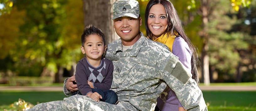 Military and veteran family sits on a lawn together